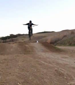 Guy on mountain bike jumping with no hands in air picture