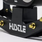 Detailed image of the engraved Hustle Bike Labs logo on the REMtech Blackjack Black pedal.
