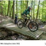 Adaptive rider on mountain bike trail, riding with magnetic pedals.