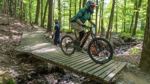Adaptive rider on mountain bike trail, riding with magnetic pedals.